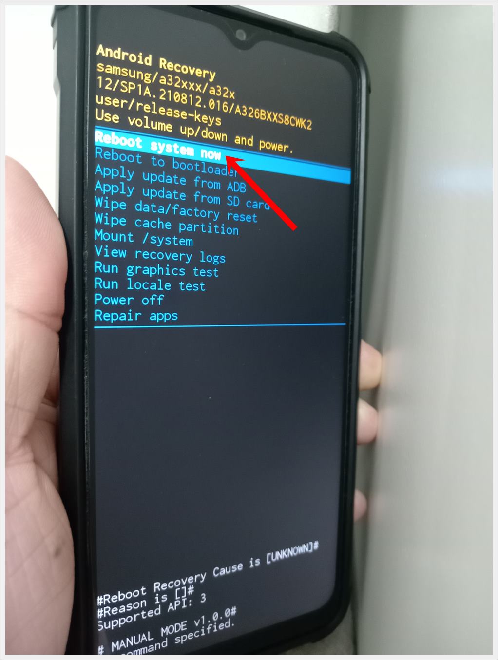 This photo shows a Samsung Galaxy phone displaying the 'Android Recovery' screen with the 'Reboot System Now' option highlighted.