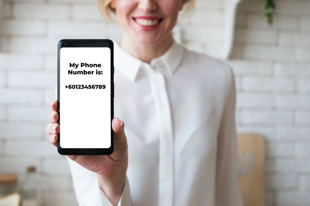 How to Check Your Phone Number: This photo depicts a woman showing her smartphone with its screen displaying her phone number.