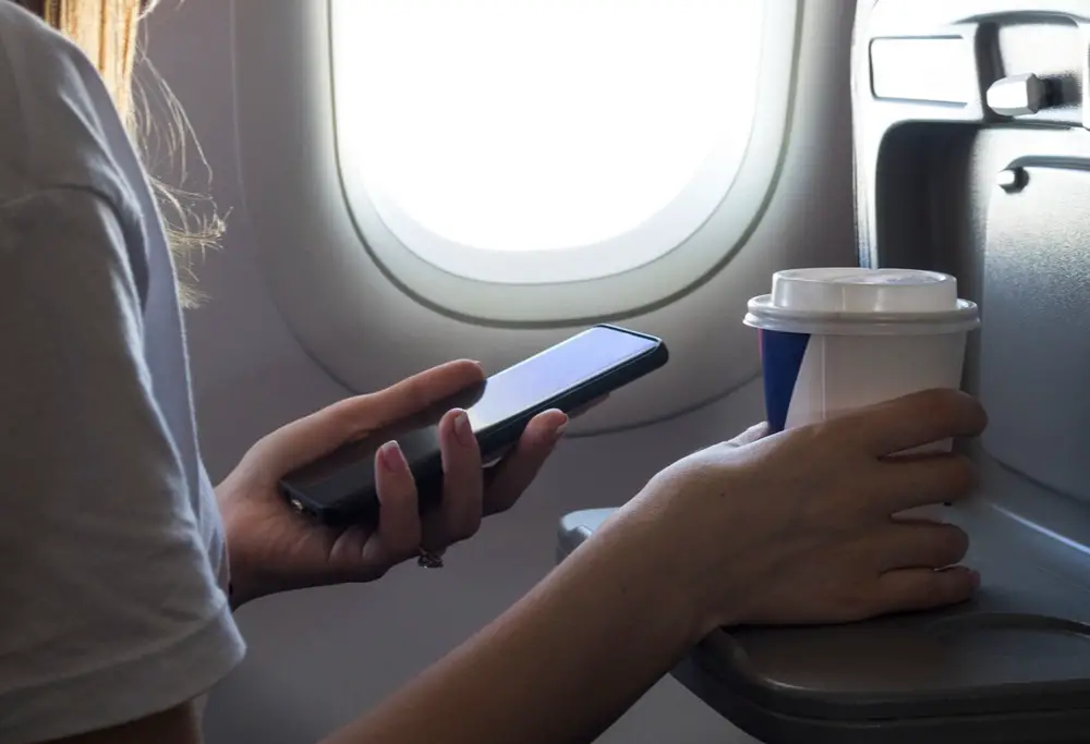 This photo depicts a woman using her smartphone on the plane.