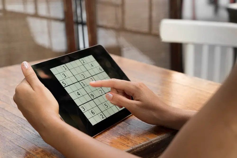 This photo depicts a woman playing a Sudoku game on her tablet.