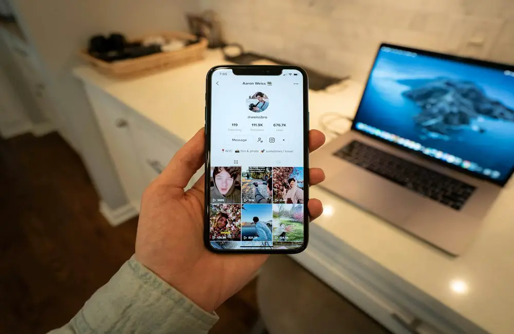 A man holding his phone, with the screen displaying his TikTok profile.